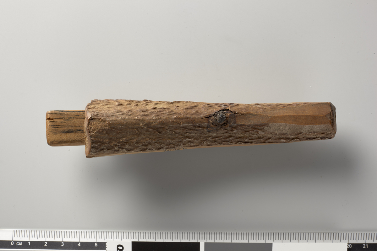 to bearbeidede Stykker Hjortehorn, firkantede, 14.5 cm. lange, 2.5 cm. brede, 1-1.6 cm. tykke; noget buede efter Hornets naturlige Form, glat afskaarne paa de tre Sider, medens den fjerde viser Hornets oprindelige Overflade. Begge Stykker ere gjennemborede midtpaa, og i den enes Hul sidder endnu en Rest af en Jernnagle.
Ved demontering av vikingtidsutstilingen i Frgt 2 våren 2018 ble det konstatert at de to stykker er blitt sammenlimt som en klemme som holder et trestykke på plass - trestykket virker moderne.