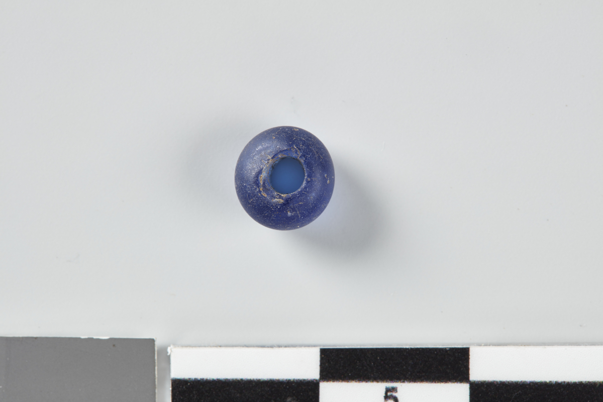 Blå, rund glassperle. Diam. 0,8 cm