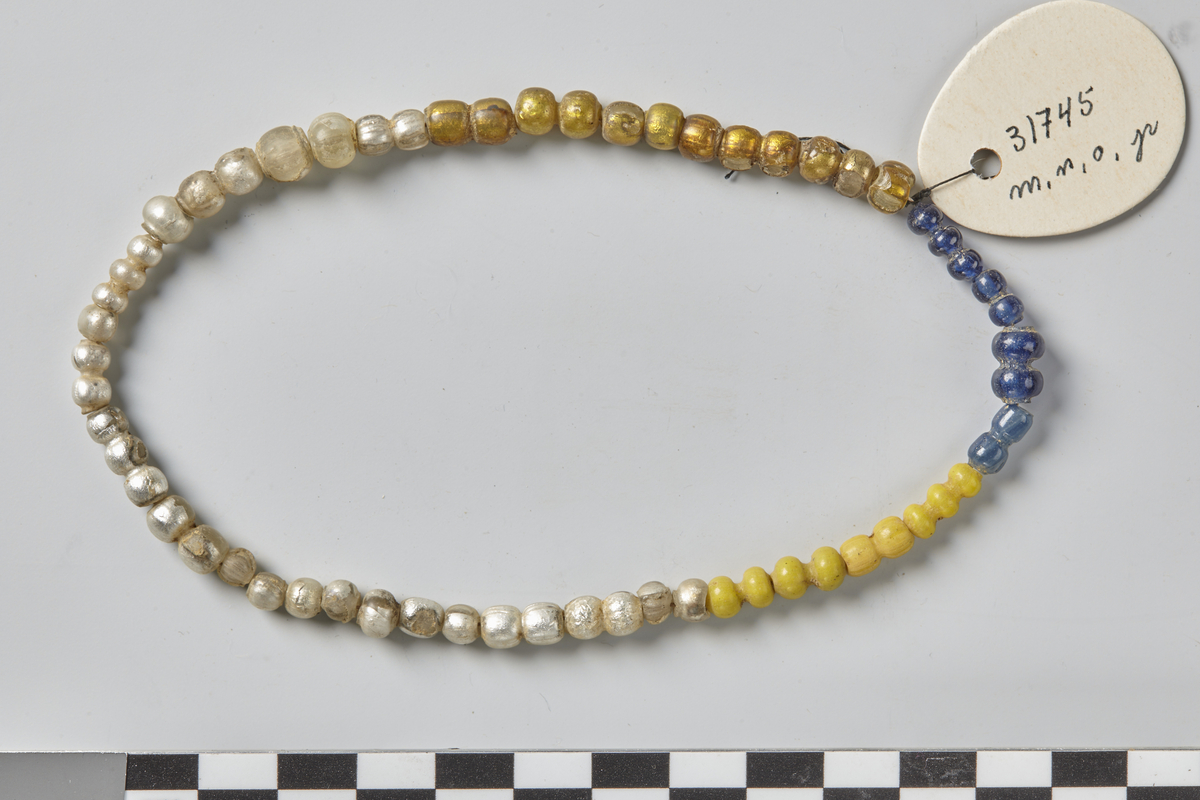 3 tre-leddete, 6 to-leddete og 13 enkle sølvfolierte, blanke glassperler, som Birka, Taf, 117, 11. Lengder: de tre-leddete 1,4 cm x 1,1 cm, de to-leddete 0,9-1,2 cm, den enkle 0,4-0,7 cm.