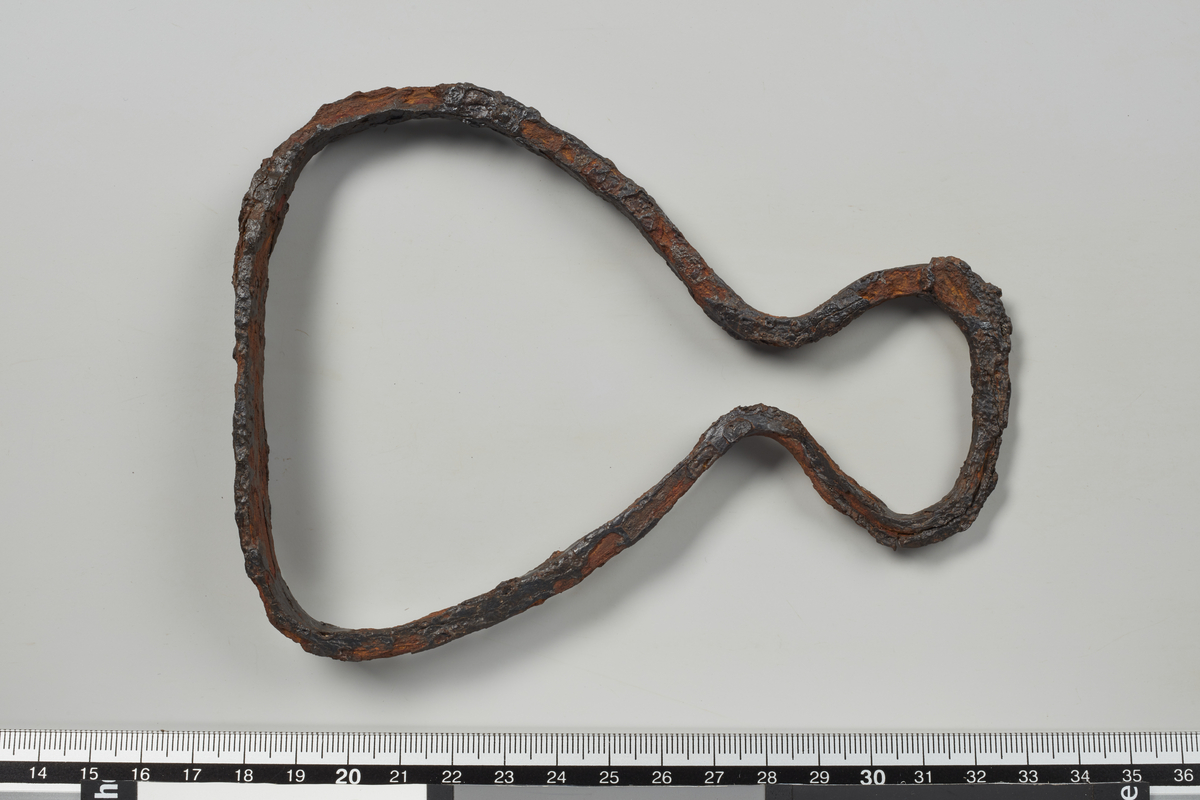 Stigbøyle, som er smidd av et stykke jern, er godt bevart. Remholderåpningen er nærmest spissoval, halsen sammenknepet, sidestengene jevnt krumme og fotplaten formet som en avlang plate. Bøylen har rektangulært tverrsnitt. L. 14,8 cm, største br. 11,2 cm, fotplaten: 2,3 x 8 cm. (funn 26)