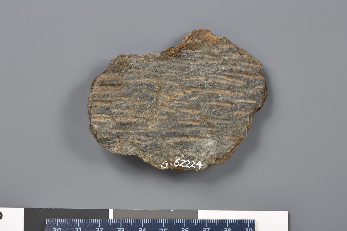Bakstehellefragment. Riller på en side. Stl: 8,3 cm, Stb: 6,7 cm, Stt: 1 cm. Vekt: 70 g. 