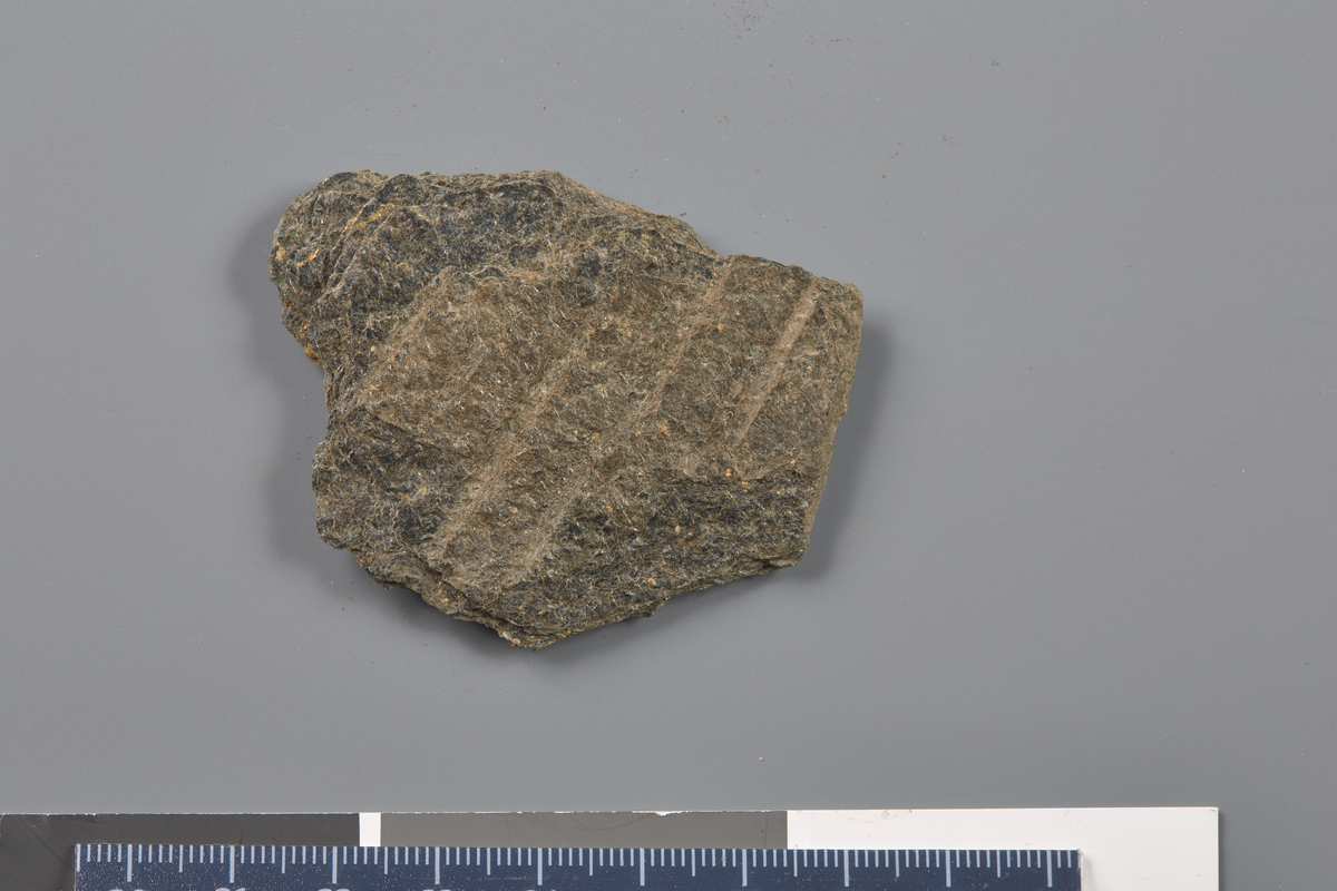 Bakstehelle av skifer. Fragment. Enkelt rillemønster som i S.S. Tengesdal, 2010, s. 25. Ytterkant. Riller på begge sider. Stl: 5,8 cm, Stb: 4,6 cm, Stt: 0,7 cm. Vekt: 26 g. 