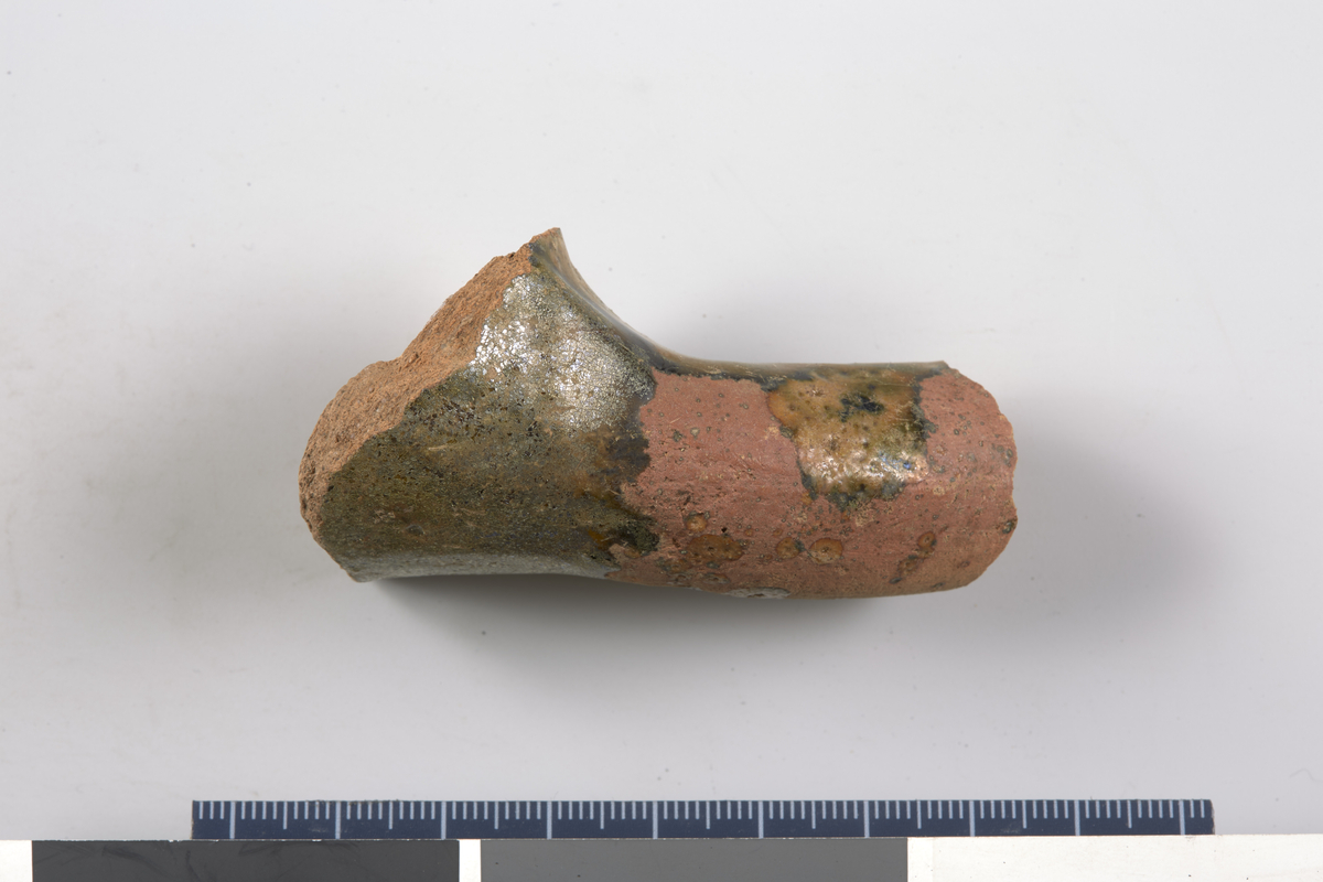 Kar. trinnformet Utvendig overflate: delvisoliven gl Godsfarge: rød Midtre farge: rød Innvendig farge: rød. Stl: 6,8 cm, Stb: 4,4 cm, Stt: 2,2 cm. Kanne av eldre rødt leirgods.