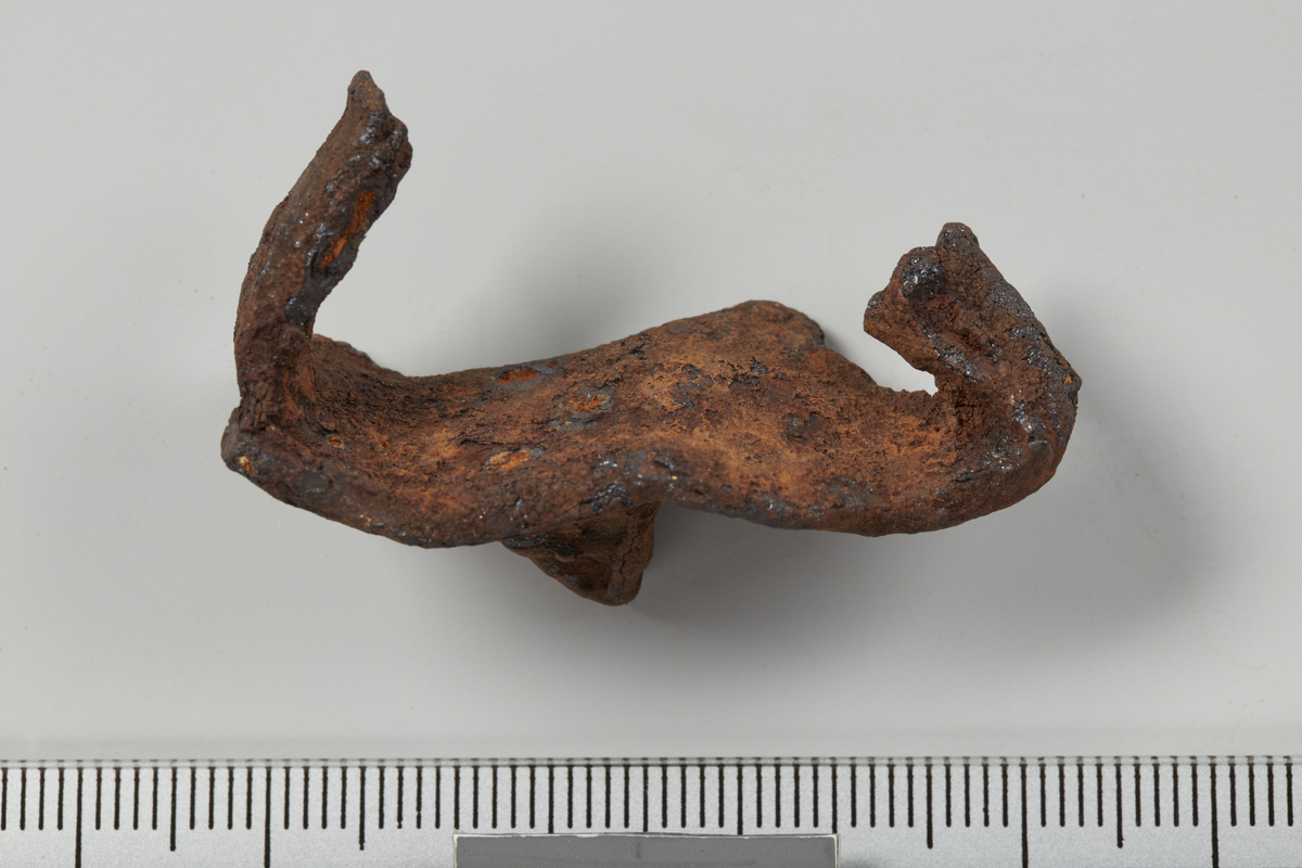 Isbrodd av jern til hest, trolig som R.591/Petersen 1951:fig. 52, men begge armer er avbrukket. L. understykke: 4,3 cm, st. bevart l. arm: 2,1 cm.