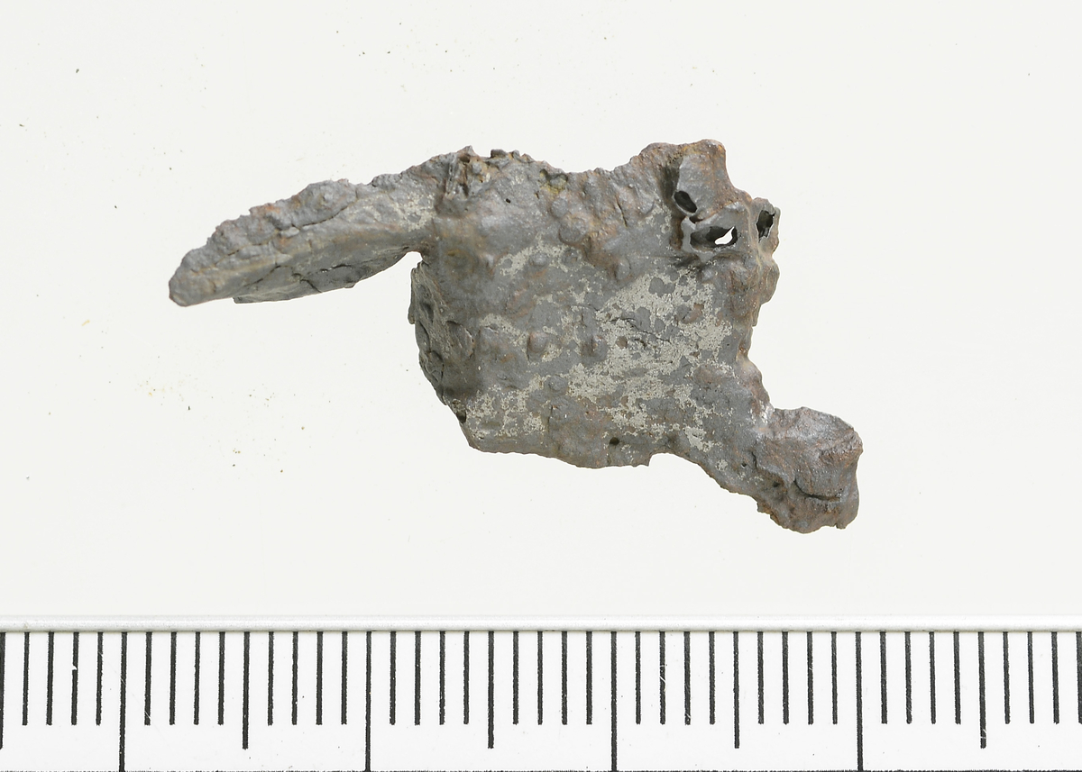 Fragment av en plate av jern. Mål: Stl: 3,0 cm. Stb: 1,5 cm. Stt: 0,6 cm. 