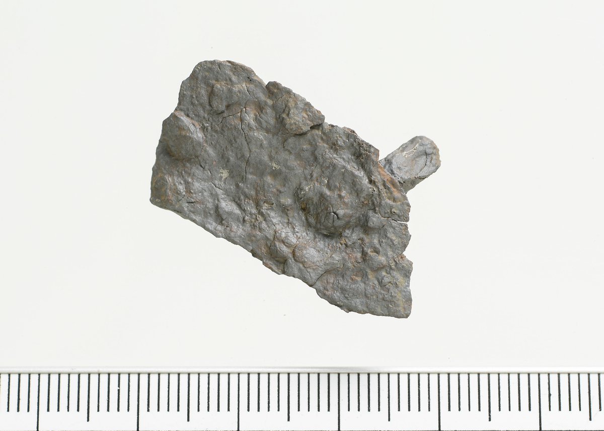 Fragment av jern. Mål: Stl: 3,2 cm. Stb: 1,7 cm. Stt: 0,3 cm. 