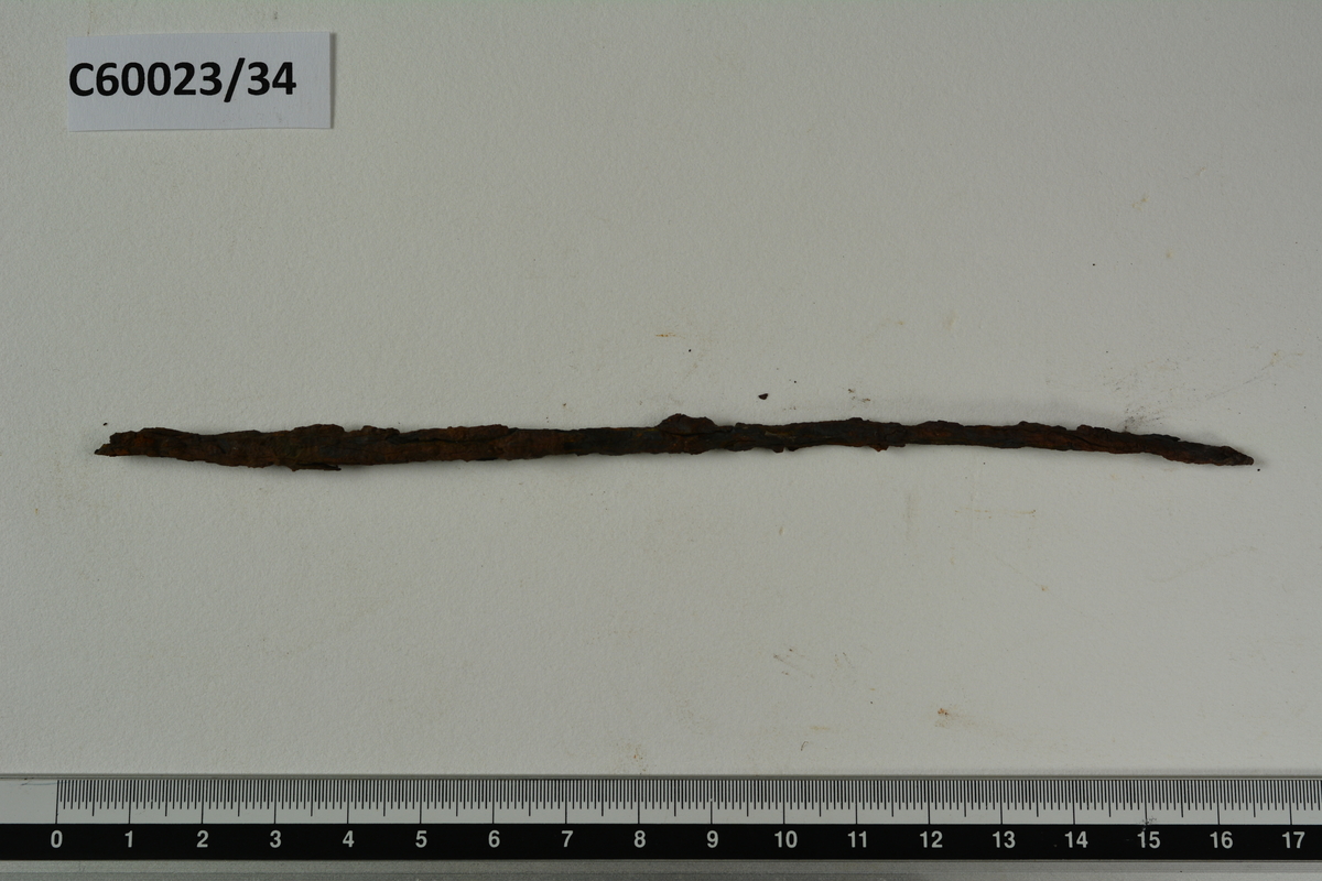 Mulig syl av jern, kan også være en rundfil. Lang, smal med jent rundt tverrsnitt, spiss i endene. L. 16 cm, diam 0,5 cm. Vekt 9,7 g.