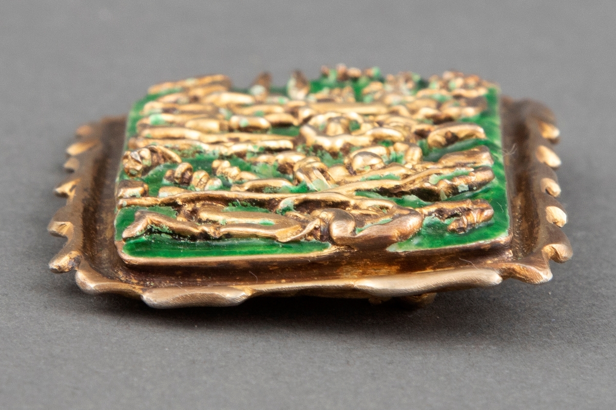 Rektangulær brosje i forgylt sølv med grønn emalje. Pastoralt motiv med fire stiliserte menneskefigurer og to dyr.