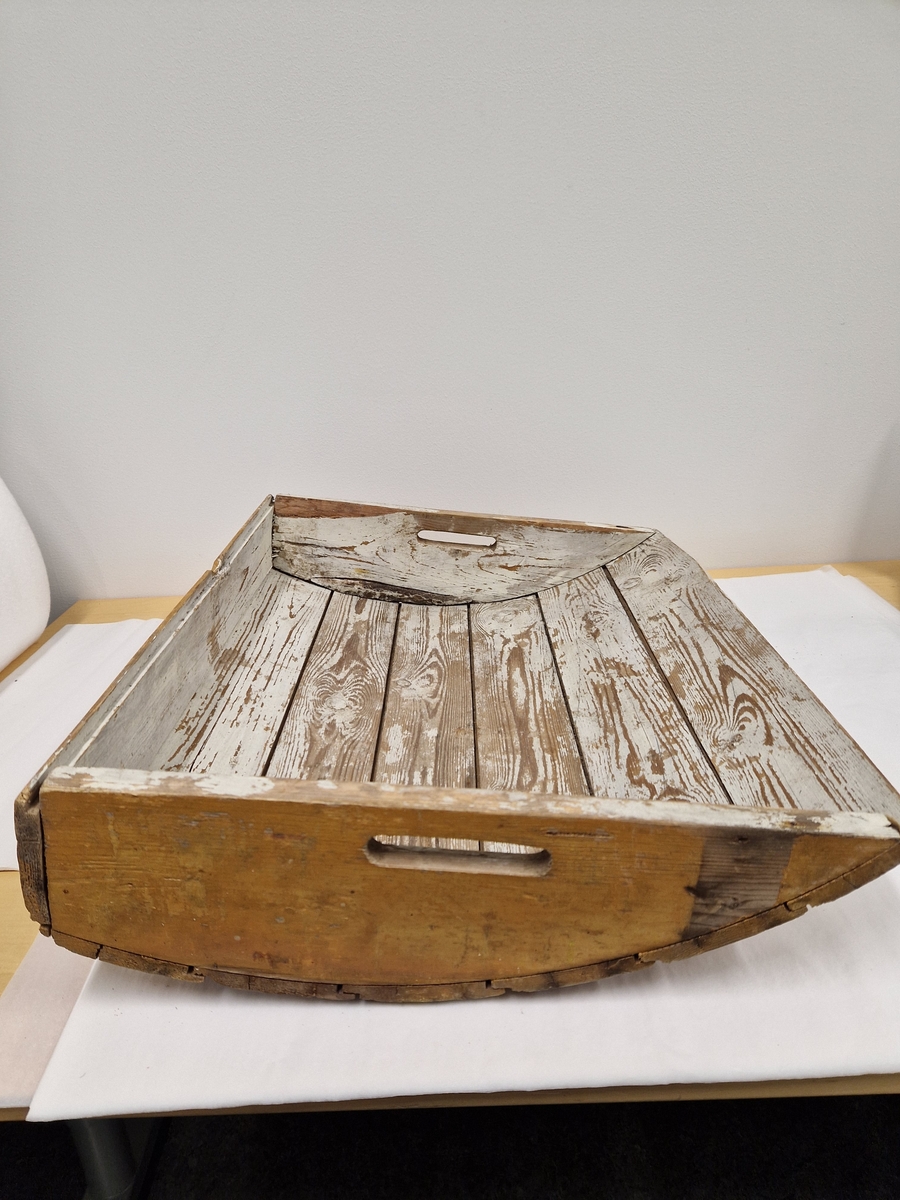 En trekasse med kuv bunn og åpninger på sidene til handtak