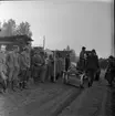 Skogsdag Örserums brunn 1961. Män står längst med en lerig väg. Det åker en traktor på vägen med en plog på släp.