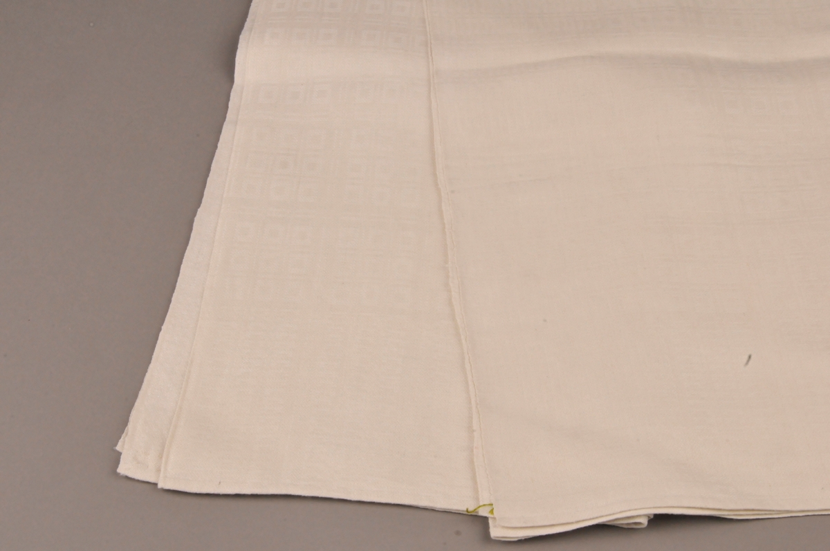 Duk av lin. Einsfarga med rutemønster. Relativt blank på rettsida. Falda med små faldesting for hand i begge kortsidene.