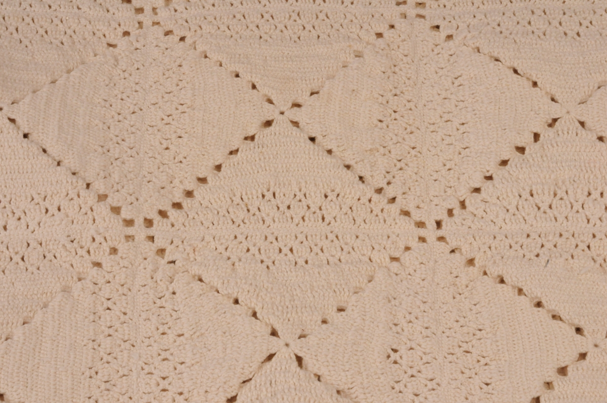 Sengeteppe hekla med rutemønster i bomull. Rutene er sett saman av trekantformer.
