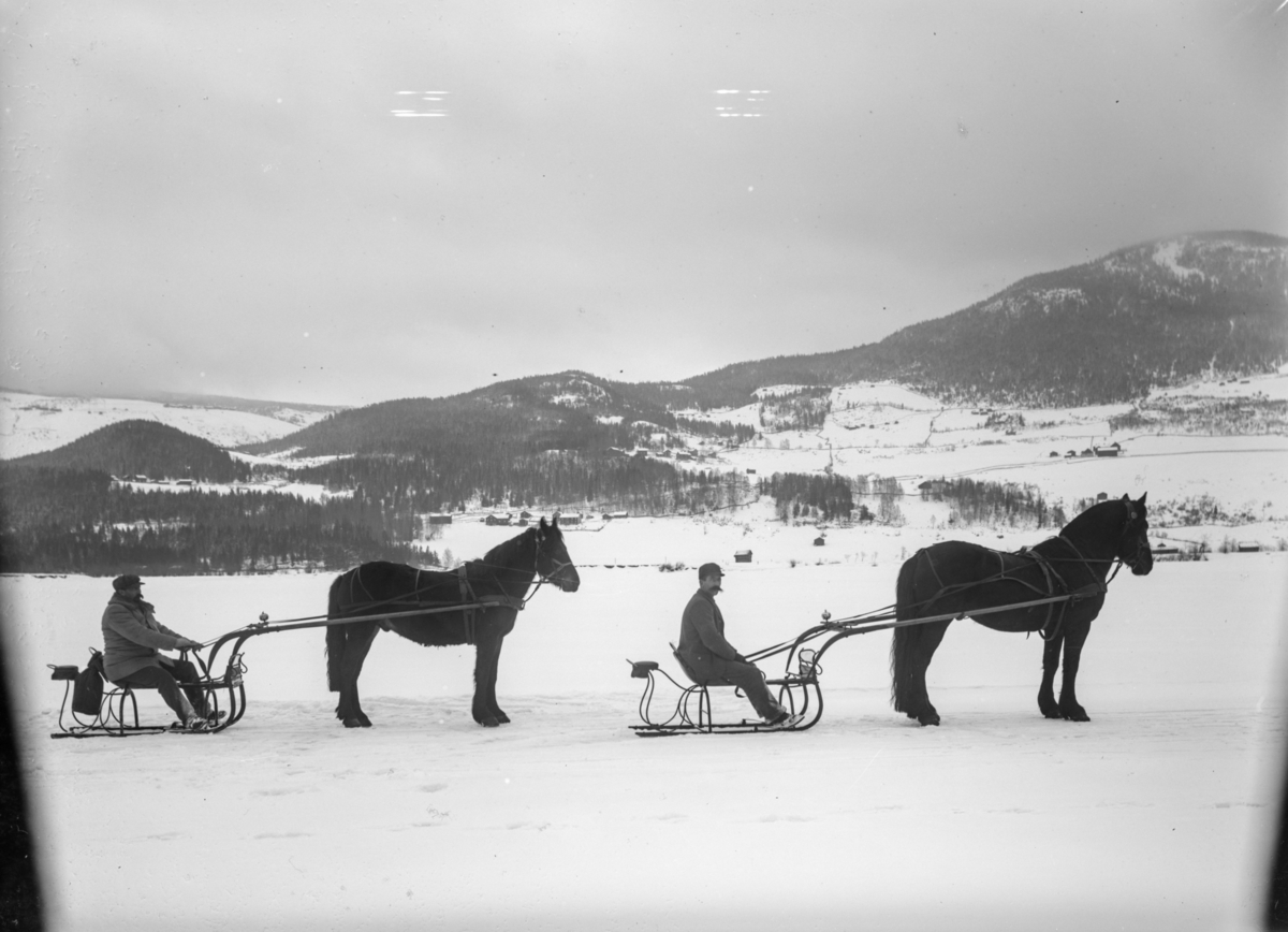 Vinterbilde med to hester og sleder på isen. I bakgrunnen utsikt mot Hånnåkampen og Oppsalåsen, sør for Fåvang sentrum, og muligens gårdene Rørvik og Lunde.