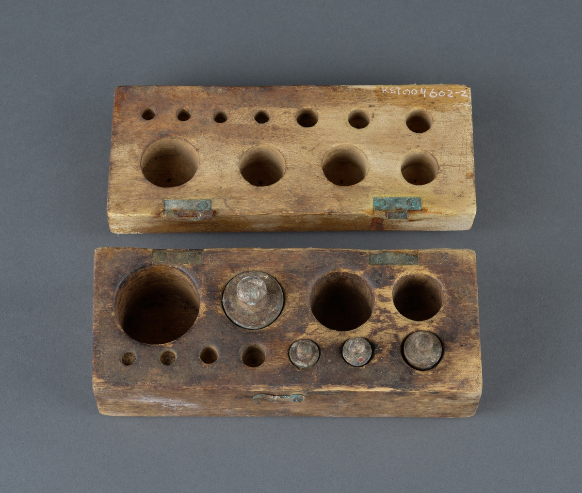 Treskrin med lodd brukt ved veiing. 
Skrinet er rektangulært med innvendig hull for de enkelte lodd.
Av de 11 lodd det er plass for, er bare 4 lodd igjen.
Er hengslet i bakkant (ødelagt) og har en krok for lukking i front. Motsats til kroken mangler, så skrinet består av løst lokk og underdel.