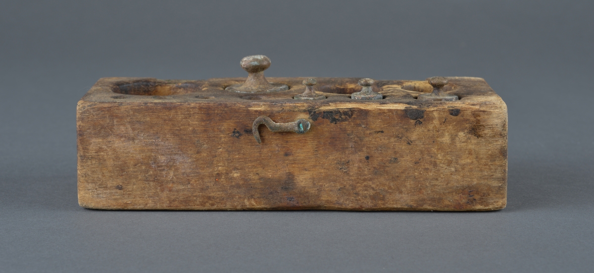 Treskrin med lodd brukt ved veiing. 
Skrinet er rektangulært med innvendig hull for de enkelte lodd.
Av de 11 lodd det er plass for, er bare 4 lodd igjen.
Er hengslet i bakkant (ødelagt) og har en krok for lukking i front. Motsats til kroken mangler, så skrinet består av løst lokk og underdel.