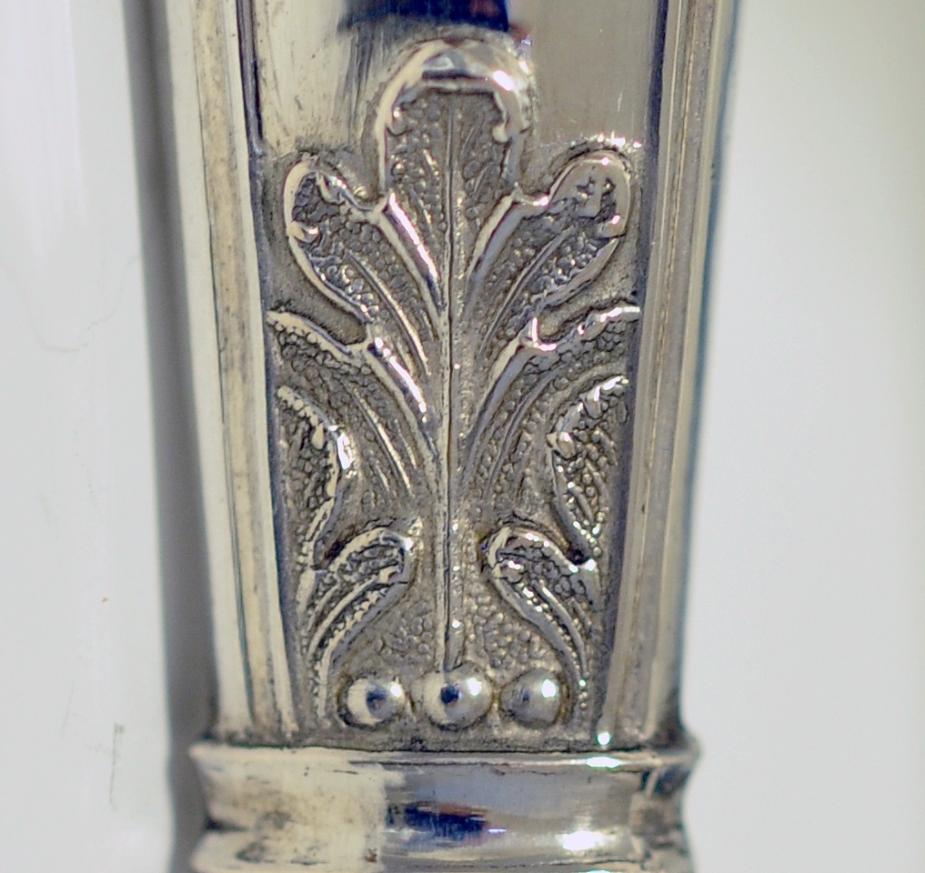 Kniv med skaft. Tilhører antakeligvis bestikksett med skje og gaffel. Bordkniv med butt knivblad. Skaftet har dekorert relieff i muslingmønster og qravert inn: C.C.C.A. 1835.(Christine Cecilie Charlotte Aall).