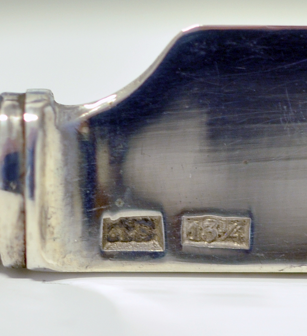 Kniv med skaft. Tilhører antakeligvis bestikksett med skje og gaffel. Bordkniv med butt knivblad. Skaftet har dekorert relieff i muslingmønster og qravert inn: C.C.C.A. 1835.(Christine Cecilie Charlotte Aall).