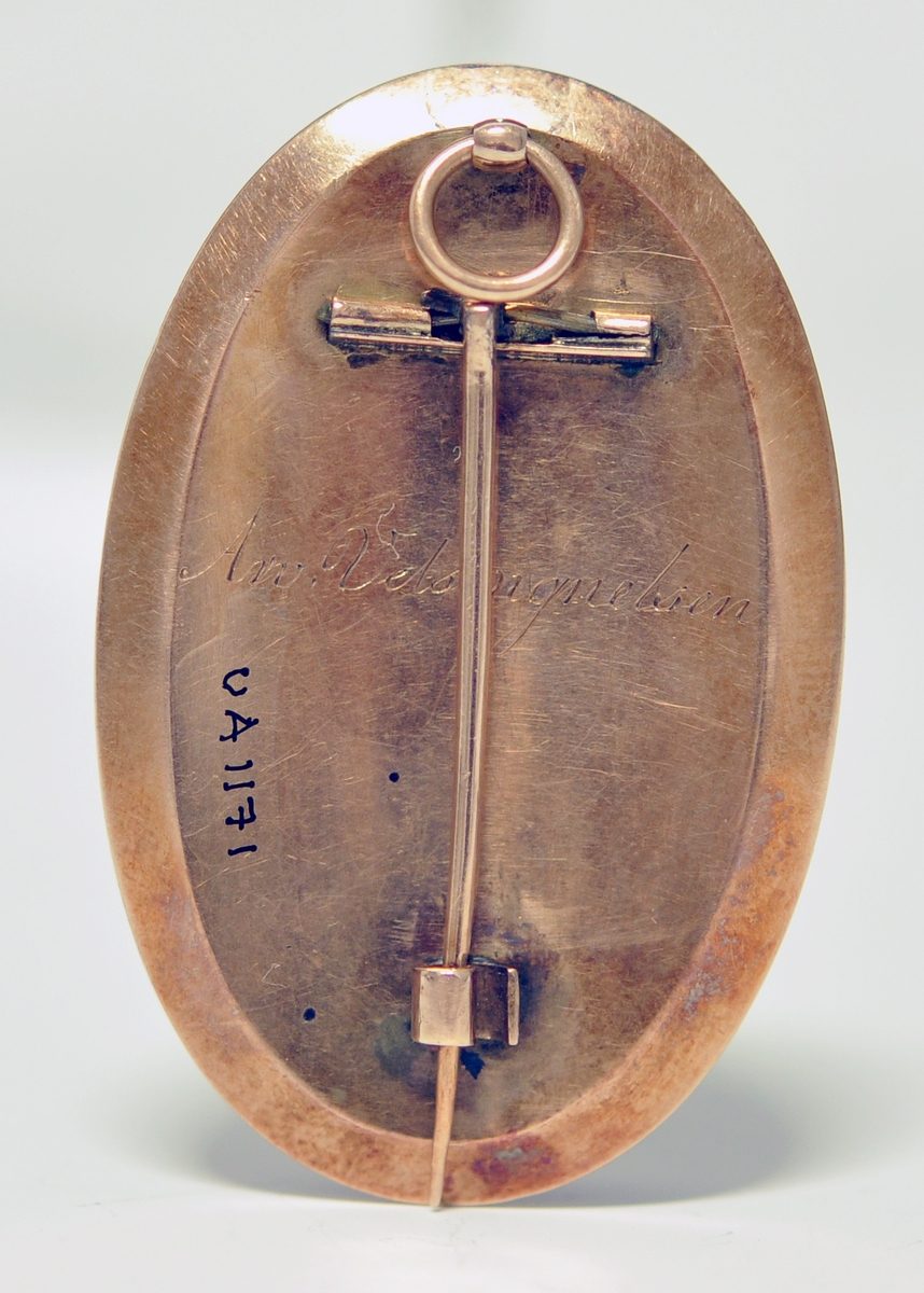 A.Oval medaljong med  antakeligvis hår sydd i rutemønster på framsiden.I midten er det montert inn en liten plate med initialene: AA. Over er det glass.Det er en blå emaljekant rundt med mønster i gull. Baksiden er av metall og det er gravert inn: Arv velsignesen. Baksiden har en påmontert nål, og det er en ring øverst til kjede.

B.Svart smykkeeske med stempel, vet ikke om den er original.