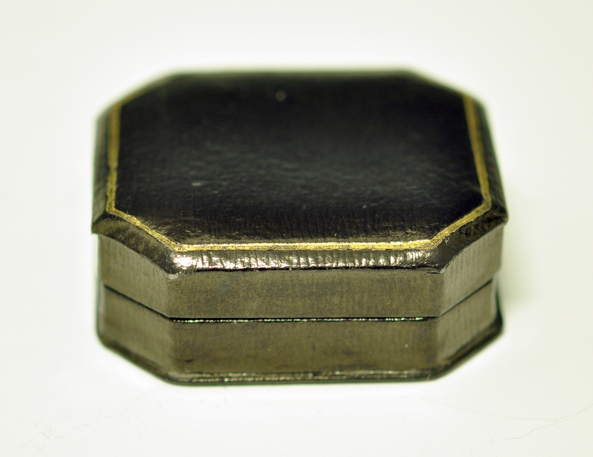 A.Oval medaljong med  antakeligvis hår sydd i rutemønster på framsiden.I midten er det montert inn en liten plate med initialene: AA. Over er det glass.Det er en blå emaljekant rundt med mønster i gull. Baksiden er av metall og det er gravert inn: Arv velsignesen. Baksiden har en påmontert nål, og det er en ring øverst til kjede.

B.Svart smykkeeske med stempel, vet ikke om den er original.
