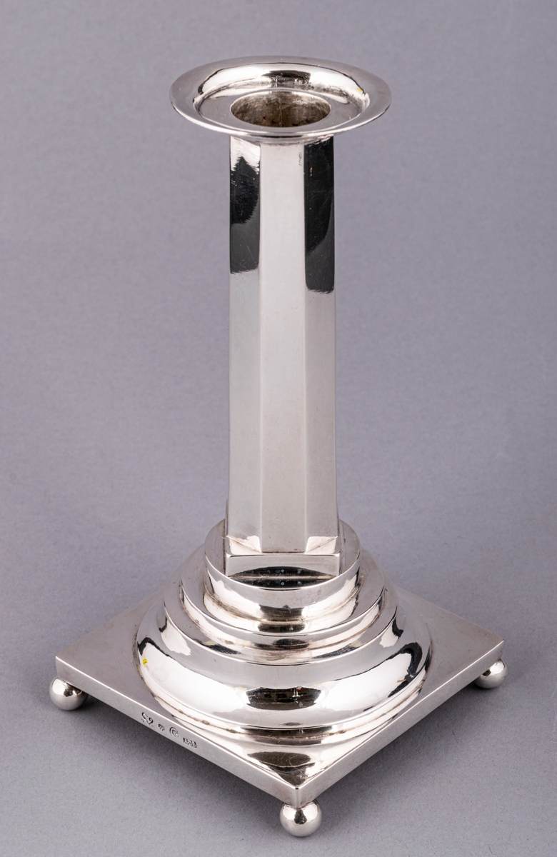 En av ett par gustavianska ljusstakar i silver stämplade Anders Dunderberg, Gävle 1800. Stram åttaformat ben med avtagbar manschett, rektangulär terrasserad fot med kulfötter. Mästarstämpel på fotens sida: S2 tre kronor G A.DB.