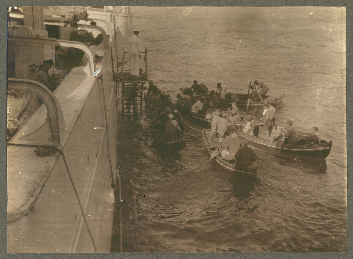 Bilden visar en grupp handlare i småbåtar som ligger långsides med Fylgia och erbjuder sina varor.