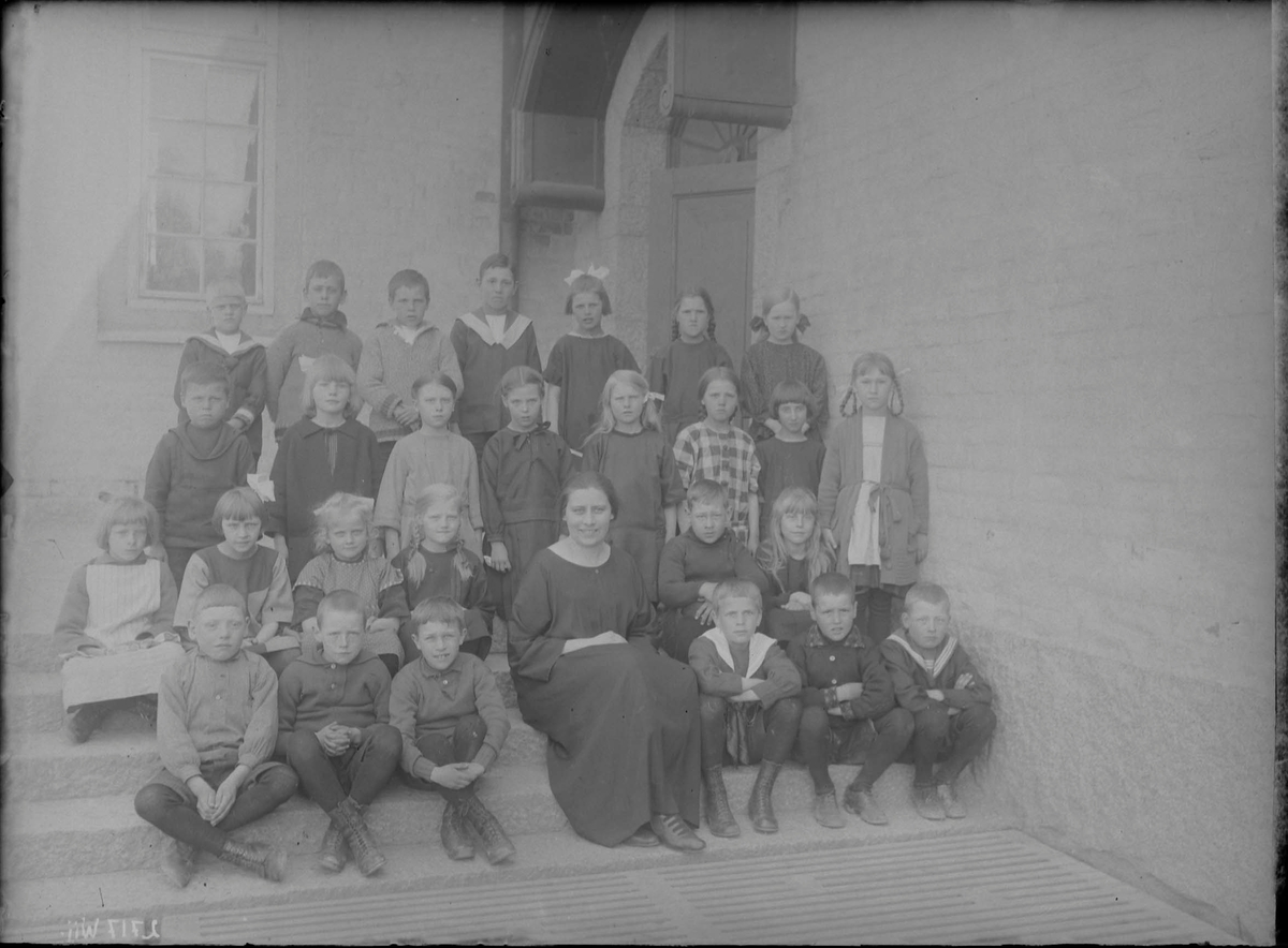 Klassen är uppställd framför skolhuset. Lärarinnan heter Hildur Linnéa Pettersson (1896-1964). De är ej identifierade.