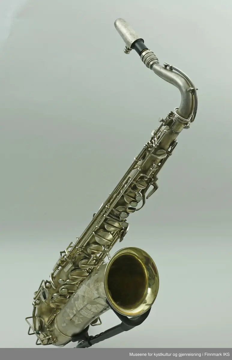 En altsaksofon med kasse produsert i Tyskland av H.G. Hüller. Laget av messing og med enkelt rørblad. Saksofonen har gravert dekor med logo av fabrikkprodusent "G.H.Hüller Saxophonefabrick Schöneck i.V". Saksofonen består av munnstykket, hals og kropp. Den har 24 klaffer med 9 knapper av perlemor. Klaffene er på innsiden dekket av et hvit kunststoff. Nummeret "43311 L" er gravert på baksiden rett ovenfor buen.
