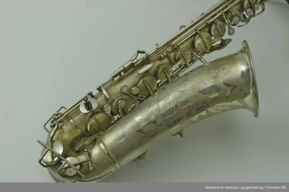 En altsaksofon med kasse produsert i Tyskland av H.G. Hüller. Laget av messing og med enkelt rørblad. Saksofonen har gravert dekor med logo av fabrikkprodusent "G.H.Hüller Saxophonefabrick Schöneck i.V". Saksofonen består av munnstykket, hals og kropp. Den har 24 klaffer med 9 knapper av perlemor. Klaffene er på innsiden dekket av et hvit kunststoff. Nummeret "43311 L" er gravert på baksiden rett ovenfor buen.