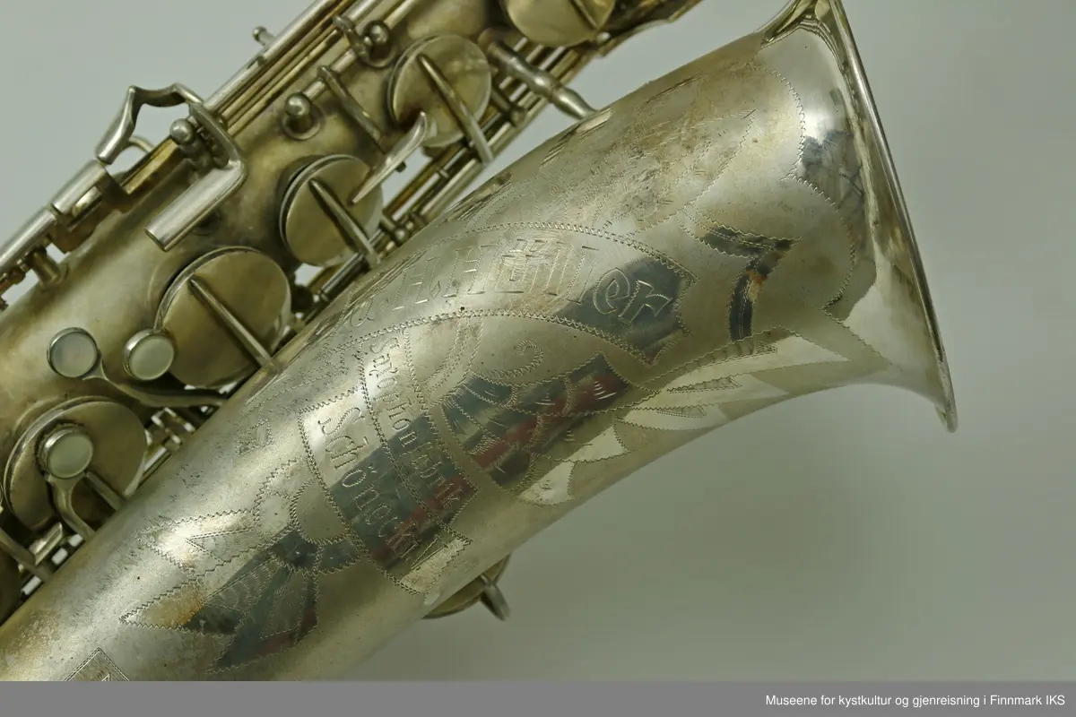 En altsaksofon med kasse produsert i Tyskland av H.G. Hüller. Laget av messing og med enkelt rørblad. Saksofonen har gravert dekor med logo av fabrikkprodusent "G.H.Hüller Saxophonefabrick Schöneck i.V". Saksofonen består av munnstykket, hals og kropp. Den har 24 klaffer med 9 knapper av perlemor. Klaffene er på innsiden dekket av et hvit kunststoff. Nummeret "43311 L" er gravert på baksiden rett ovenfor buen.