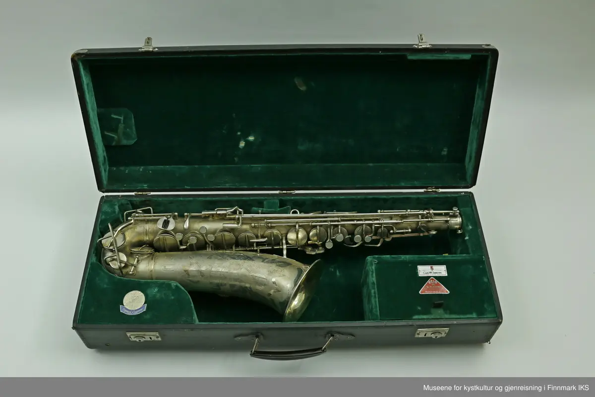 En altsaksofon med kasse produsert i Tyskland av H.G. Hüller. Laget av messing og med enkelt rørblad. Saksofonen har gravert dekor med logo av fabrikkprodusent "G.H.Hüller Saxophonefabrick Schöneck i.V". Saksofonen består av munnstykket, hals og kropp. Den har 24 klaffer med 9 knapper av perlemor. Klaffene er på innsiden dekket av et hvit kunststoff. Nummeret "43311 L" er gravert på baksiden rett ovenfor buen.