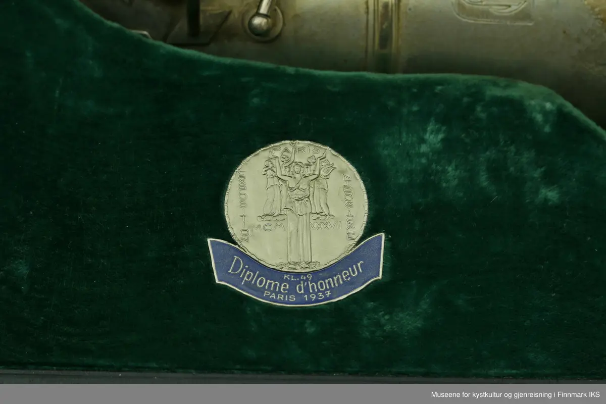 En altsaksofon med kasse produsert i Tyskland av H.G. Hüller. Laget av messing og med enkelt rørblad. Saksofonen har gravert dekor med logo av fabrikkprodusent "G.H.Hüller Saxophonefabrick Schöneck i.V". Saksofonen består av munnstykket, hals og kropp. Den har 24 klaffer med 9 knapper av perlemor. Klaffene er på innsiden dekket av et hvit kunststoff. Nummeret "43311 L" er gravert på baksiden rett ovenfor buen.