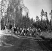 En grupp unga scouter står uppställda för fotografering. De står på en lerig väg vid ett skogsbryn.