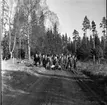 En grupp unga scouter står uppställda för fotografering. De står på en lerig väg vid ett skogsbryn.