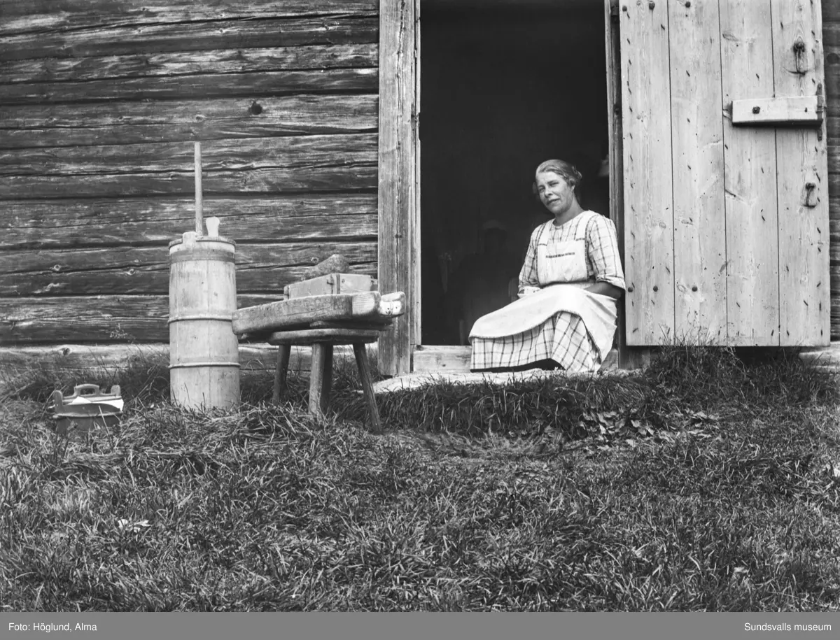 Gruppbild vid ingången till en fäbodstuga, sju vuxna och ett barn. Längst till vänster står Niklas Bergström. På bild nummer två sitter en av kvinnorna ensam i dörröppningen och utanför står smörkärna, ostformar och laggkärl.