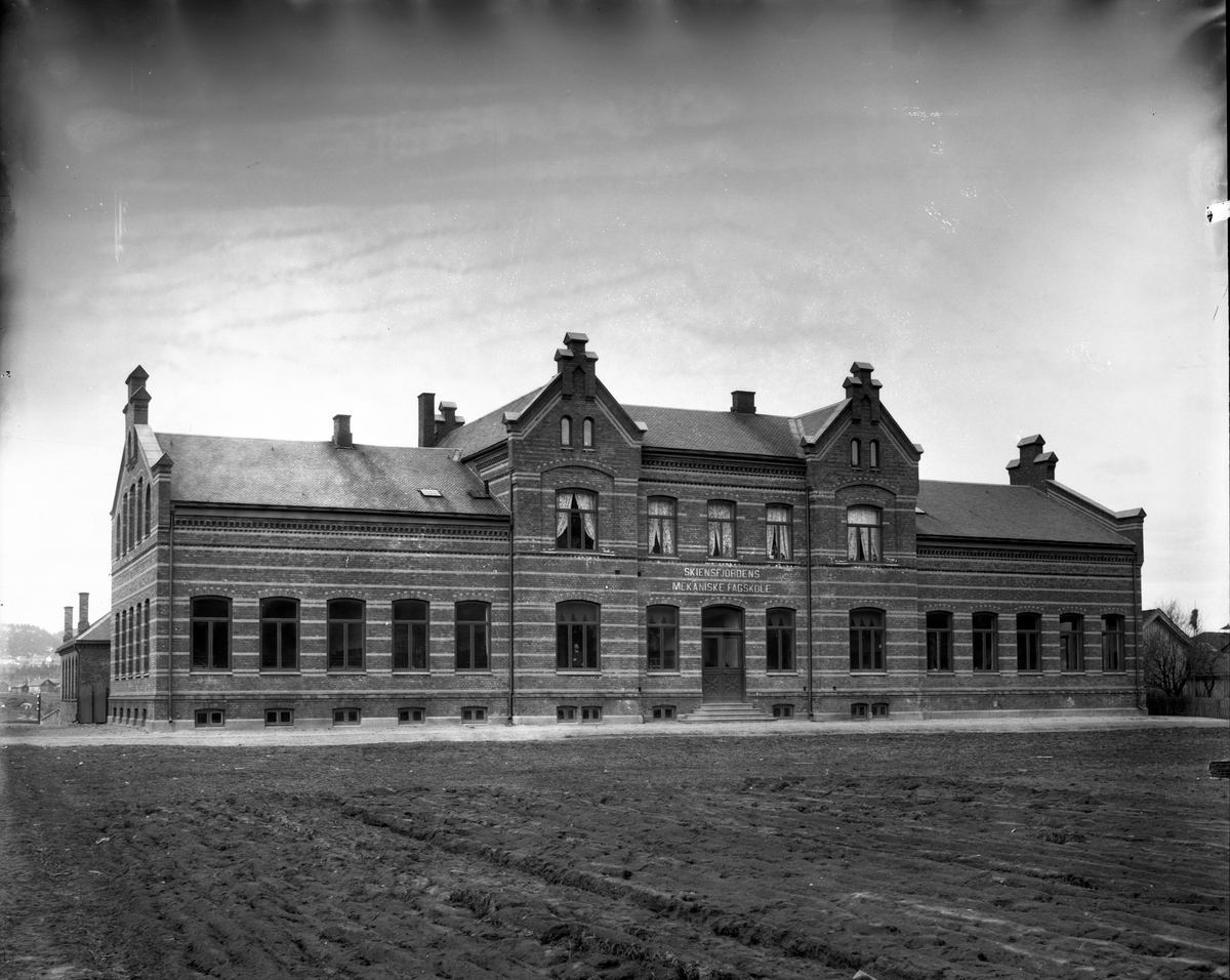 Fotosamling etter fotograf John Nielsen, Porsgrunn. Motiv med Skiensfjorden Mekaniske Fagskole på Osebakken. Fasade mot Skiensgate.