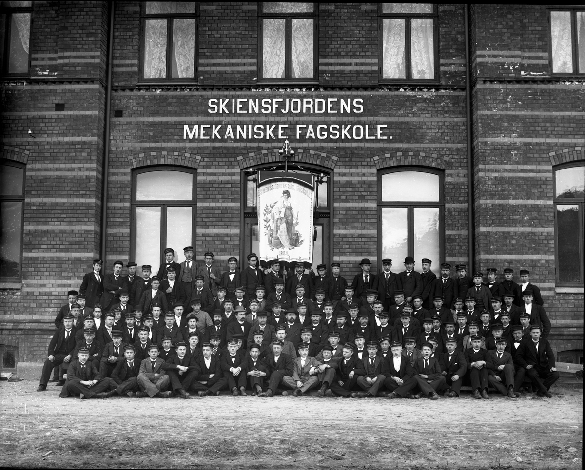 Fotosamling etter fotograf John Nielsen, Porsgrunn. Gruppeportrett av elever ved Skiensfjorden Mekaniske Fagskole på Osebakken. Årskullet 1896-1897. Elevene har sort studenterlue på. Hvit lue ble brukt mellom 17 mai og 14 oktober.
