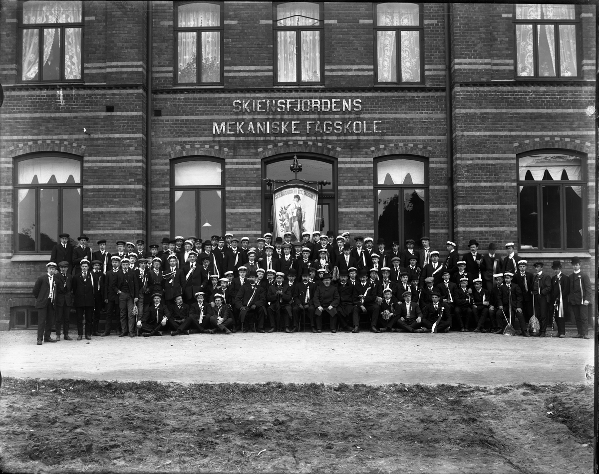 Fotosamling etter fotograf John Nielsen, Porsgrunn. Gruppeportrett av elever ved Skiensfjorden Mekaniske Fagskole på Osebakken.  Elevene har hvit studenterlua på. Hvit lue ble brukt mellom 17 mai og 14 oktober og gruppeportrettet er antakelig fotografert i forbindelse med 17 mai-feiring.
