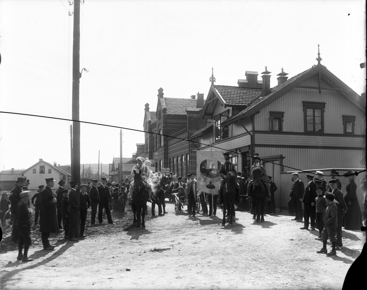 Fotosamling etter fotograf John Nielsen, Porsgrunn. Motiv med elever gående og til hest ved Skiensfjorden Mekaniske Fagskole på Osebakken. Studentene har avmars på 17. maitoget "Rampetoget", året 1910.