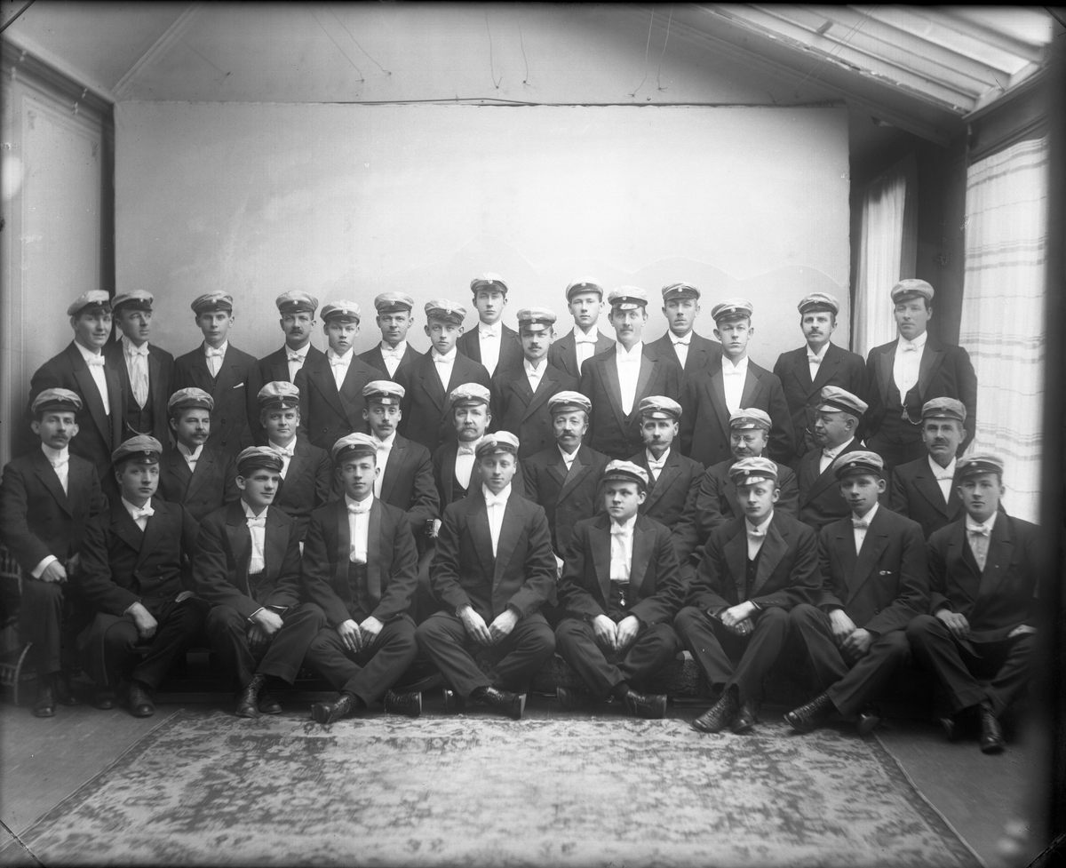 Fotosamling etter fotograf John Nielsen, Porsgrunn. Gruppeportrett og elever ved Skiensfjorden Mekaniske Fagskole på Osebakken. Studentene sees med sommerlue på.