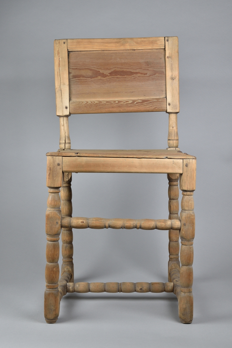 Stol tillverkad i björk och furu. Enkel delvis genombruten rygg med svarvade ryggstolpar. Enkel ostoppad sits. Stolen står på fyra profilsvarvade ben, vilka stabiliseras av svarvad framslå samt ett svarvat H-format benkryss. 