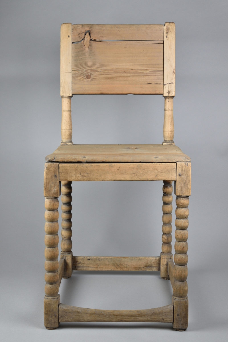 Stol tillverkad i furu. Enkel delvis genombruten ryggbricka med två svarvade ryggstolpar. Enkel ostoppad sits. Stolen står på fyra svarvade ben, vilka i nederkant stabiliseras av fyra slåar. 