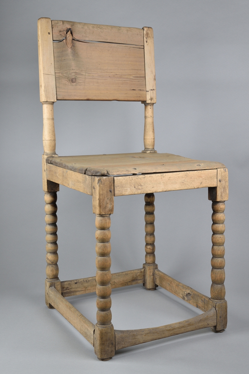 Stol tillverkad i furu. Enkel delvis genombruten ryggbricka med två svarvade ryggstolpar. Enkel ostoppad sits. Stolen står på fyra svarvade ben, vilka i nederkant stabiliseras av fyra slåar. 