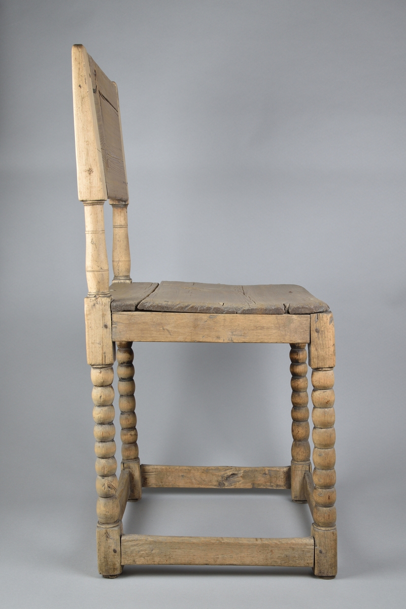 Stol tillverkad i furu. Enkel delvis genombruten ryggbricka med två svarvade ryggstolpar. Enkel ostoppad sits. Stolen står på fyra svarvade ben, vilka i nederkant stabiliseras av fyra slåar. 