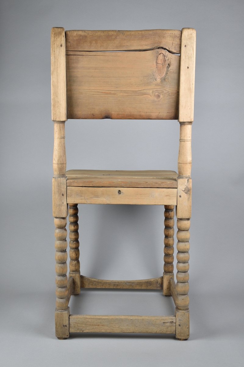 Stol tillverkad i furu. Enkel delvis genombruten ryggbricka med två svarvade ryggstolpar. Enkel ostoppad sits. Stolen står på fyra svarvade ben, vilka i nederkant stabiliseras av fyra slåar. 
