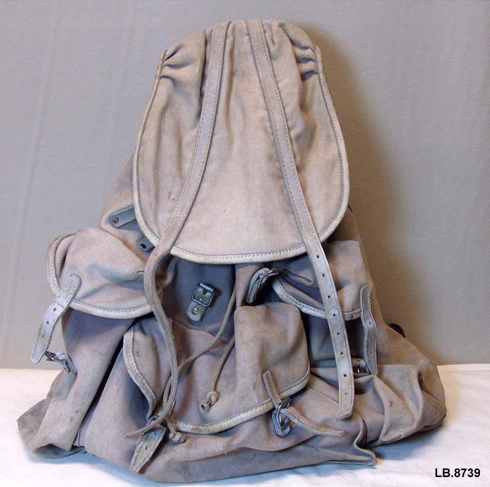 Sekk med bereramme.Laga av tjukt lerret.Ei stor lomme og to mindre. Spenner med lærreimar.