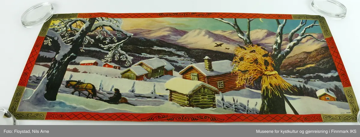 En rektangulær papirplakat med påtrykt vintermotiv av en snødekt fjellgård, et tre med julenek og fugler, en person med hest og slede. I bakgrunnen er det flere andre fjellgårder omgitt av skog og høye fjelltopper. Plakaten har en rød og gullfarget kant med mønsterdekor. Nederst i venstre hjørne står "Mittet 700/008 I", og i høyre hjørne står det "printed in Norway".