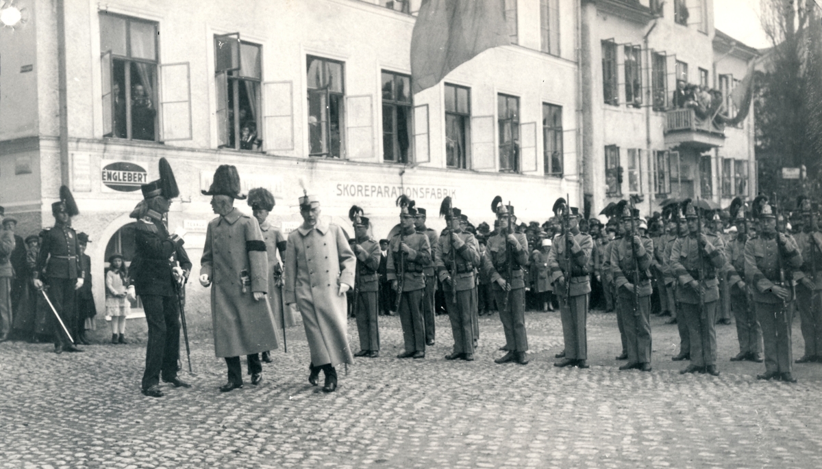 Strängnäs den 6 juni 1923

Bild 1
HM Konungen visiterar hedersvakten.

Bild 2
Konungen i samspråk med regementschefen. Husen i bakgrunden är nu rivna, men det närmaste huset är återuppbyggt i samma stil. Sedan 1994 används det av gymnasiet Europaskolan.