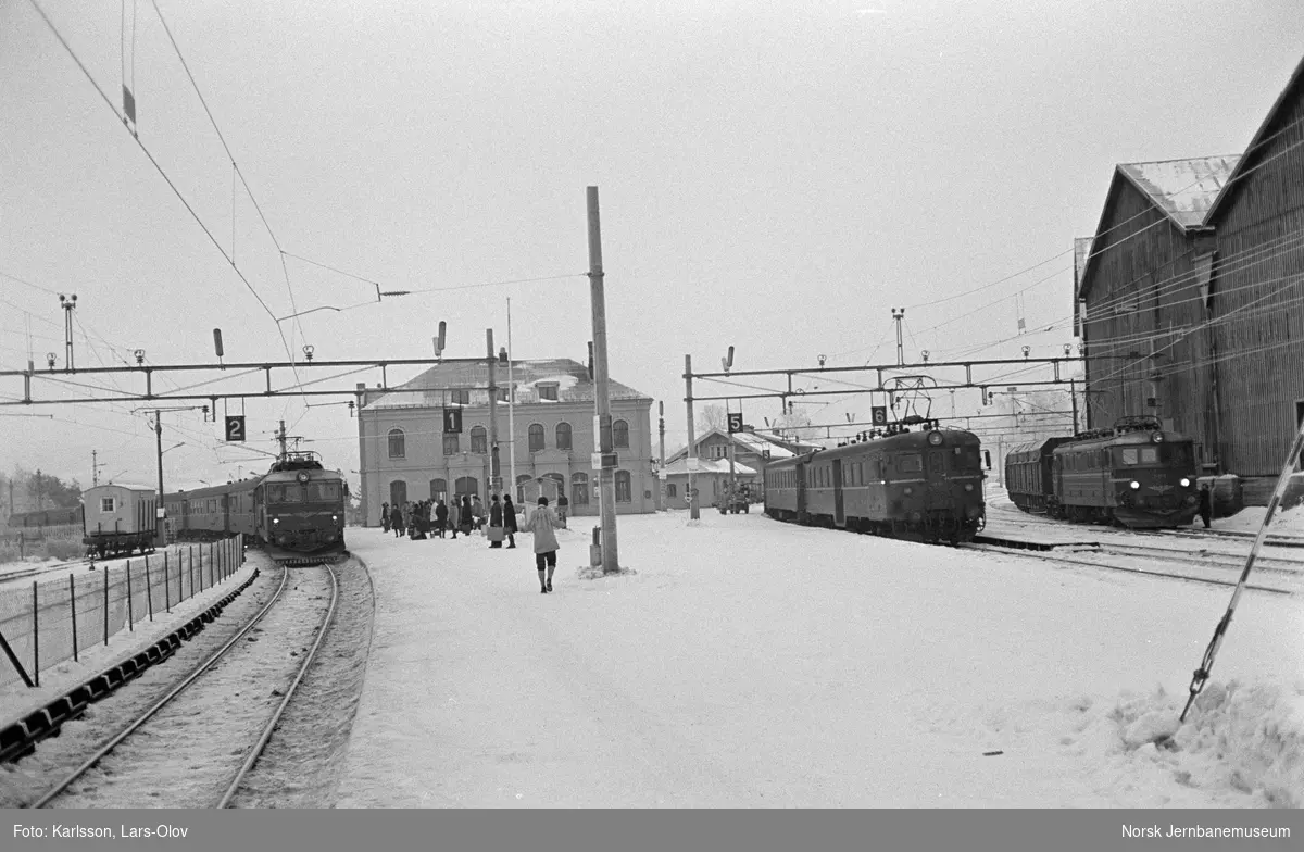 Elektrisk lokomotiv El 14 2176 med dagtoget fra Oslo Ø til Bergen, tog 601, i spor 1 på Hønefoss stasjon. I midten motorvognsett type 68 med motorvogn BM 69A 13 fremst med persontog fra Drammen, tog 527. Til høyre elektrisk lokomotiv El 11 2112 med flisvogner