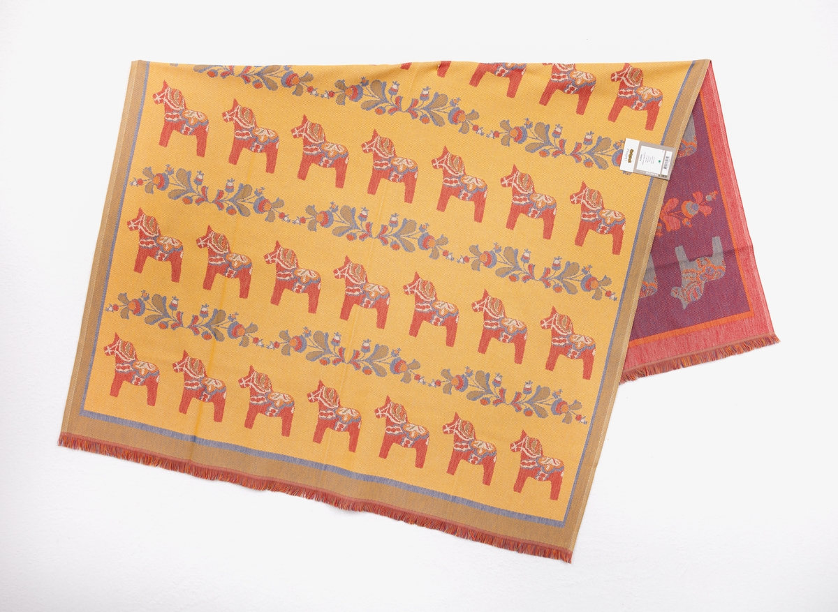 Filt, pläd vävd av bomullsgarn i flera färger. Dalahästar och kurbitser.
Ekelund RAINBOW collection "Kurbits" Design: Gudrun Jakobsson.