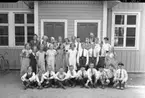 Gruppbild med en skolklass stående på en grusplan framför sin skola.